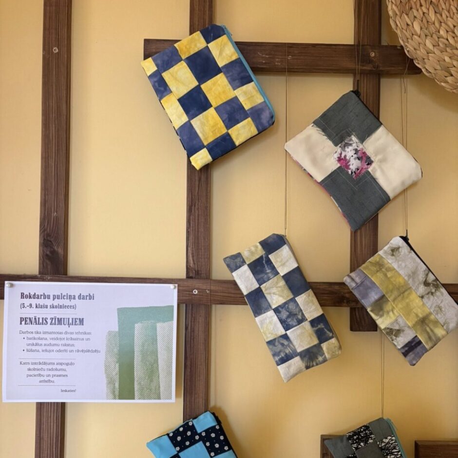 Uz dzeltenas sienas ar koka rāmjiem izvietoti seši ar rokām darināti, stepēti penāļi. Blakus tiem atrodas balta zīme ar tekstu 